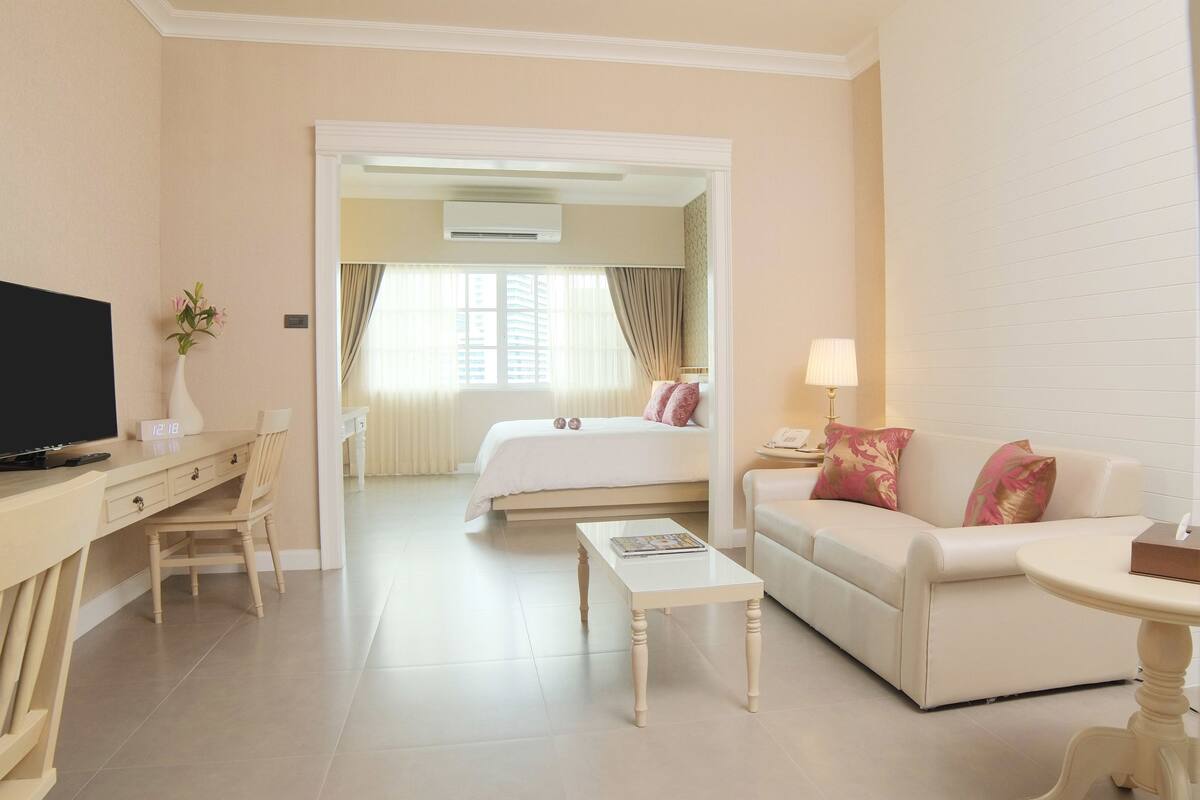 Ein Hotelzimmer mit Bett, Schreibtisch, Fernseher, Couchtisch und Sofa.