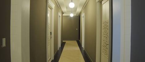 A hallway with a light fixture, doors, and a patterned wall.