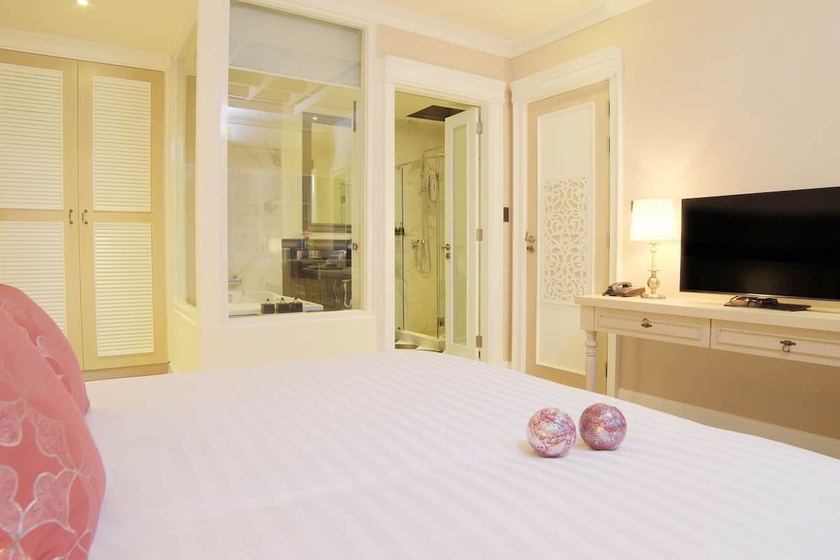 Ein Hotelzimmer mit Bett, Fernseher, Schreibtisch und einem durchgegangenen Tür erkennbaren Badezimmer.