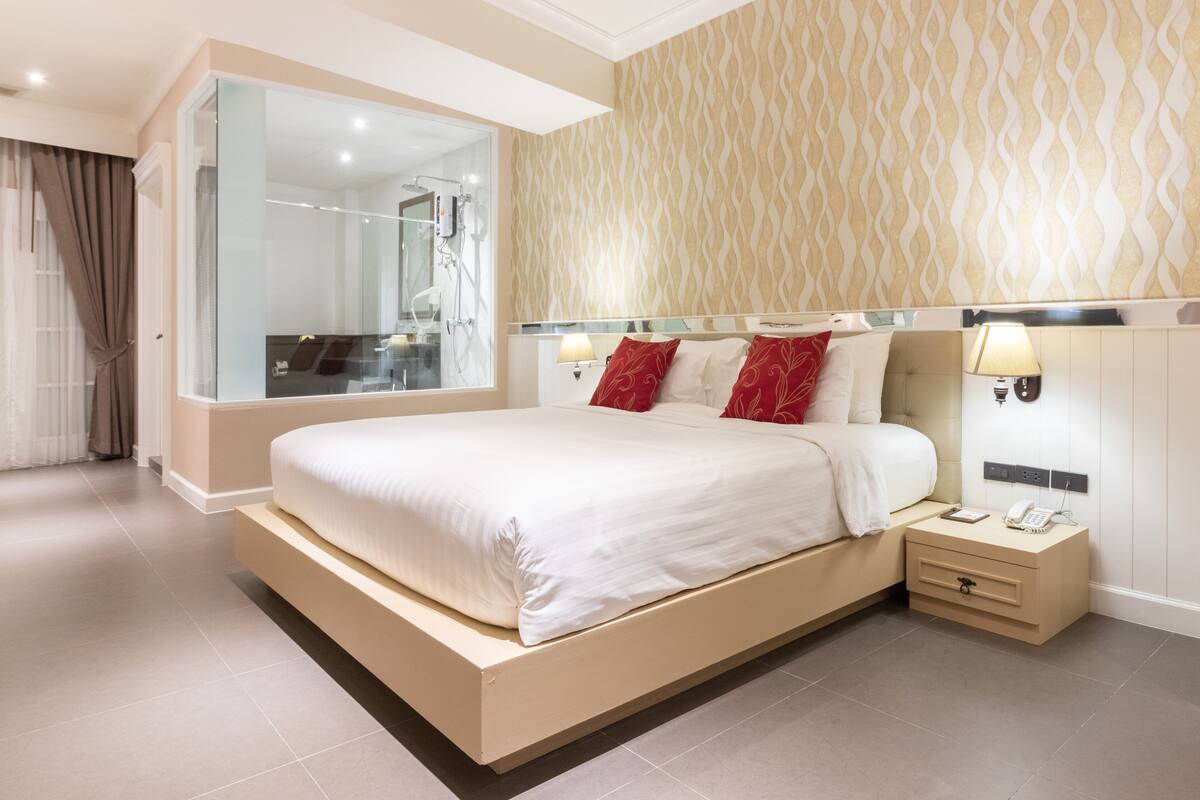 Ein modernes Hotelzimmer mit einem großen Bett, Nachttischen, einem Spiegel und einer Duschkabine.