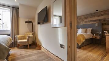 Un dormitorio moderno con una cama grande, una silla, un televisor y suelo de madera.