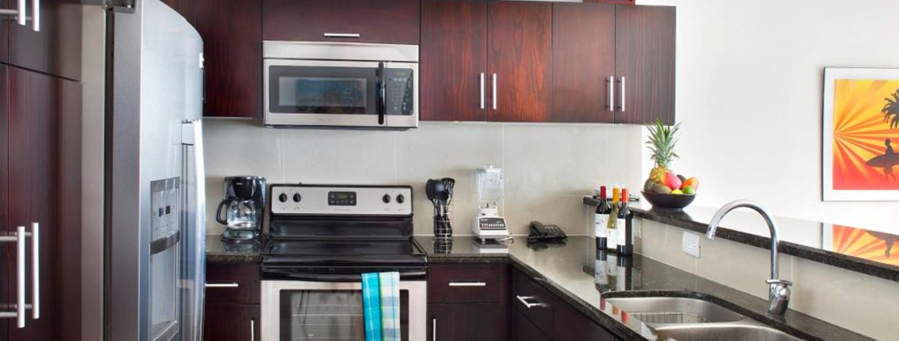 A modern kitchen with dark wood cabinets, stainless steel appliances, and a granite countertop.
