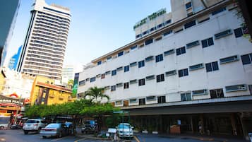 A multi-story hotel with a flat facade, numerous windows, and a parking lot in front.