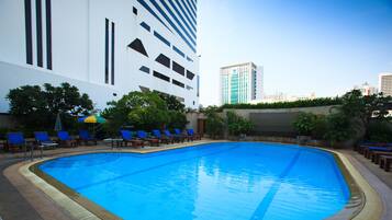 A swimming pool with blue water, surrounded by lounge chairs and potted plants.