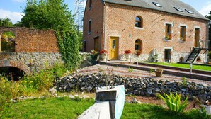 Un bâtiment en briques avec une porte jaune, une arche en pierre et un escalier menant à un deuxième étage.