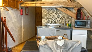 Une cuisine de taille réduite, équipée d’un four à micro-ondes, d’un évier et de meubles de rangement en bois.