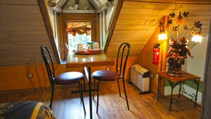Une pièce mansardée chaleureuse, avec une table en bois, deux chaises, un radiateur et une statue décorative.