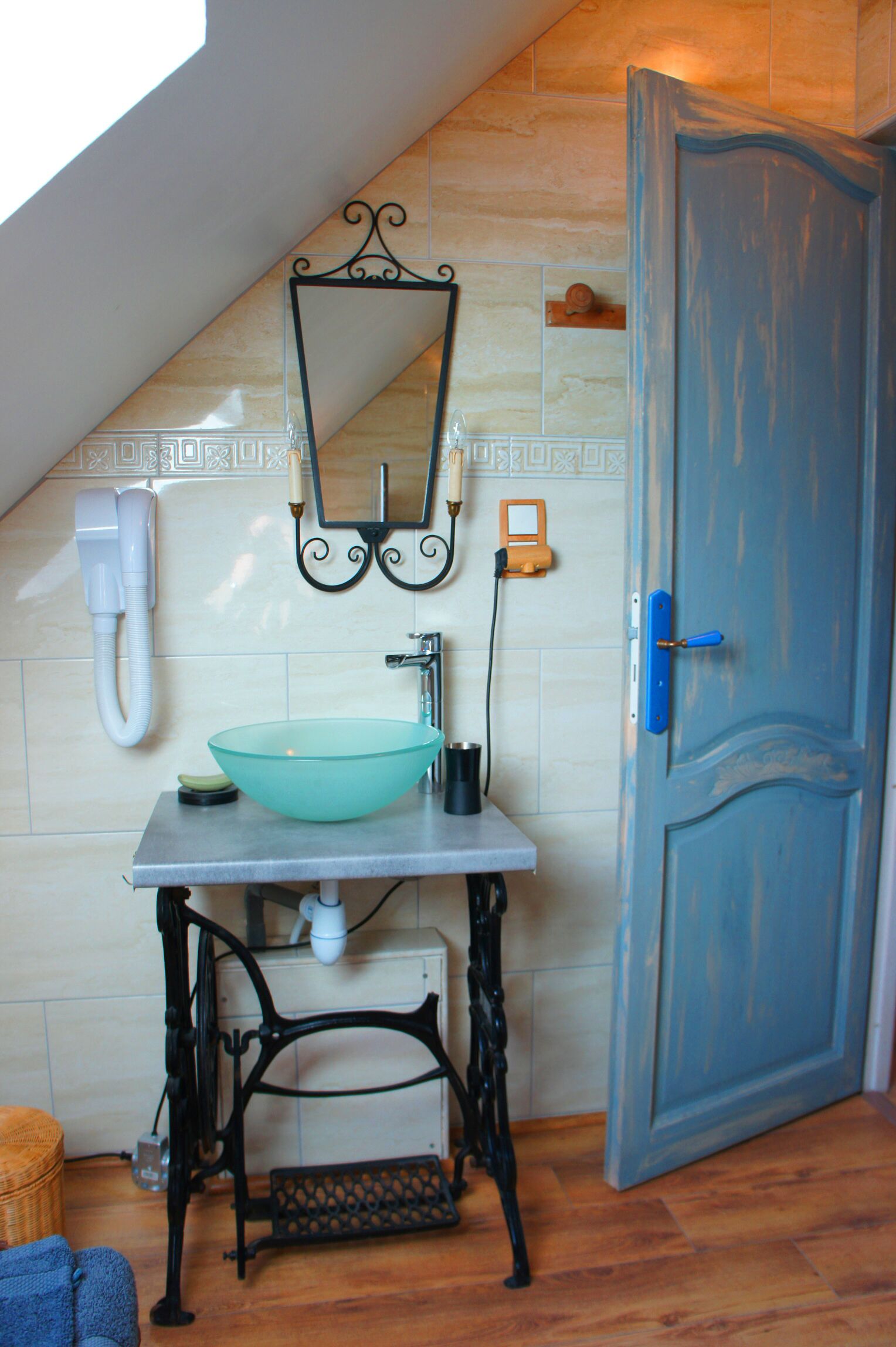 A bathroom with a glass bowl sink, a mirror, a telephone, and a door.