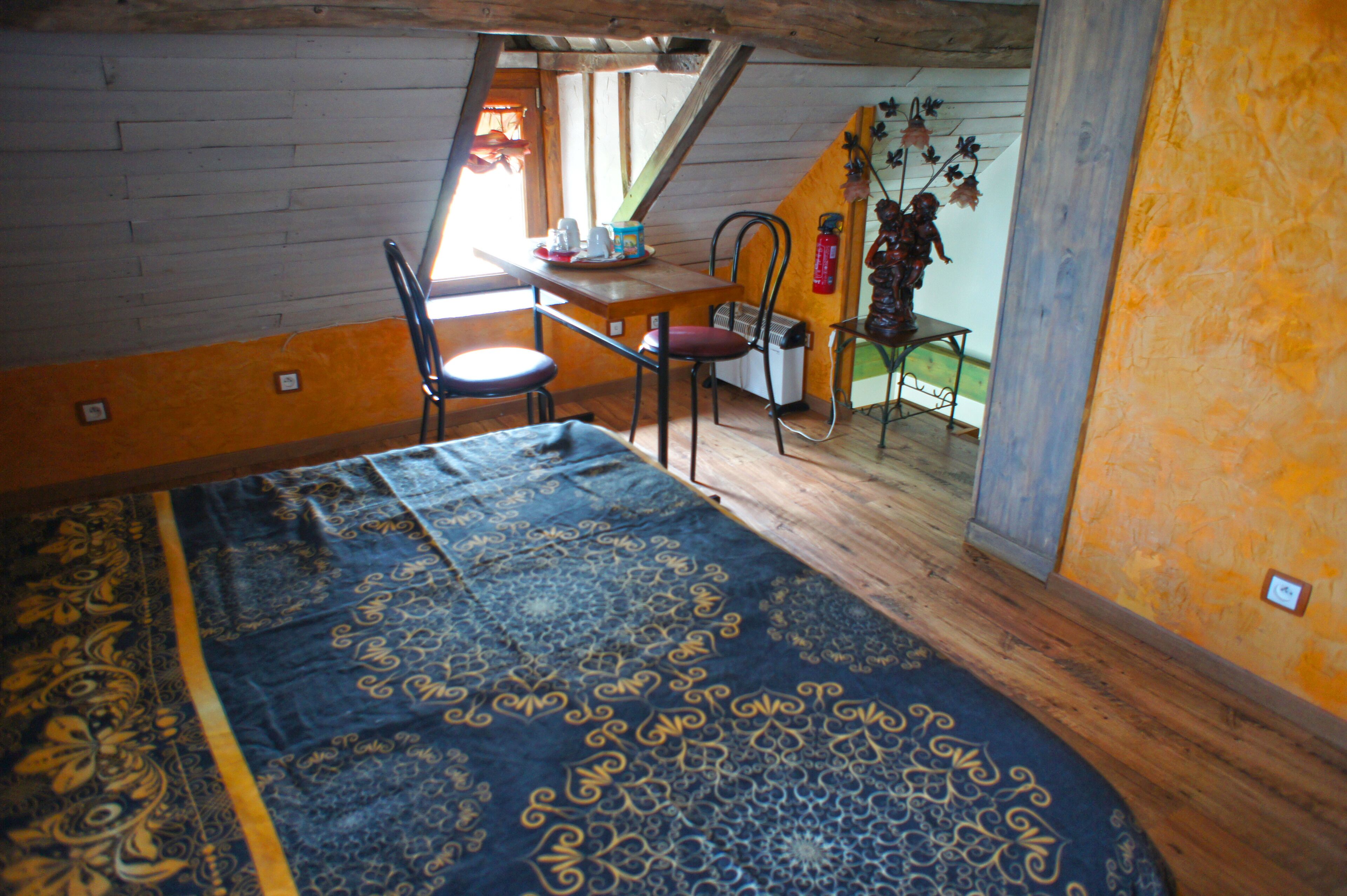 Ein Zimmer mit einem Bett, einem Tisch und einem Stuhl. Ein Fenster bietet einen Blick nach draußen.
