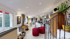 Un moderno vestíbulo de hotel con zona de comedor, una escalera y vistas al exterior.
