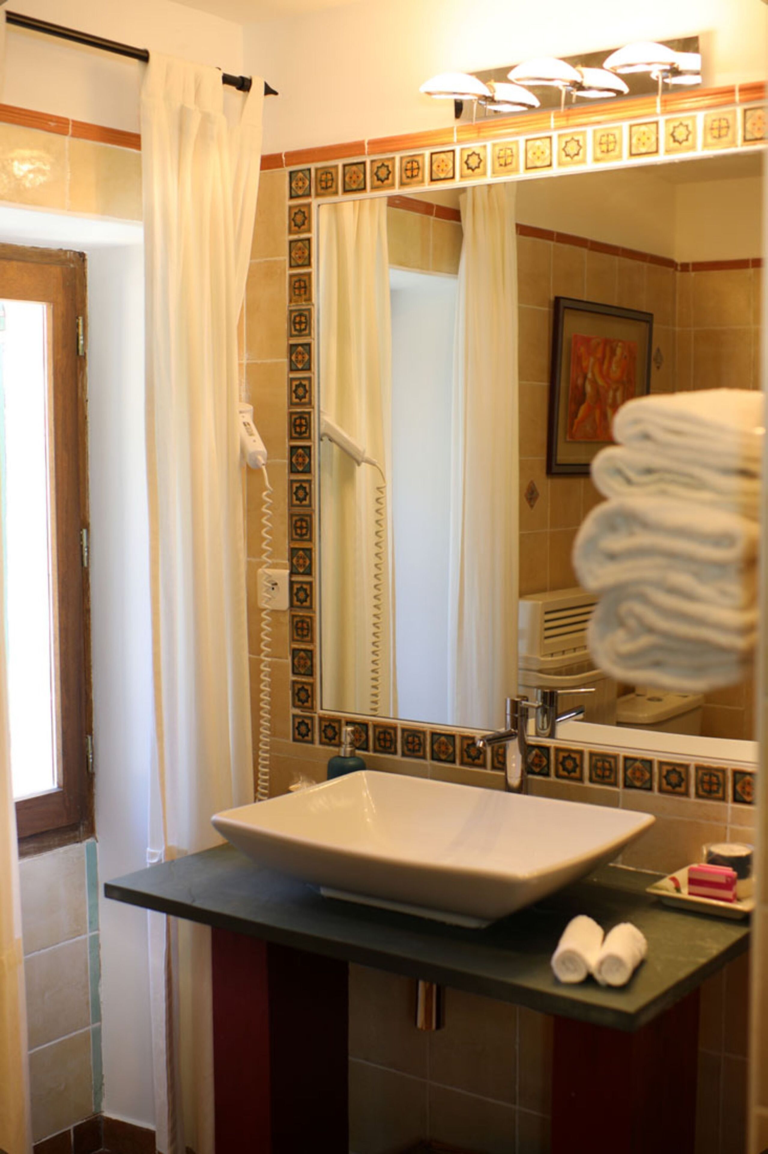Une salle de bain avec un grand miroir, un lavabo et un rideau de douche.