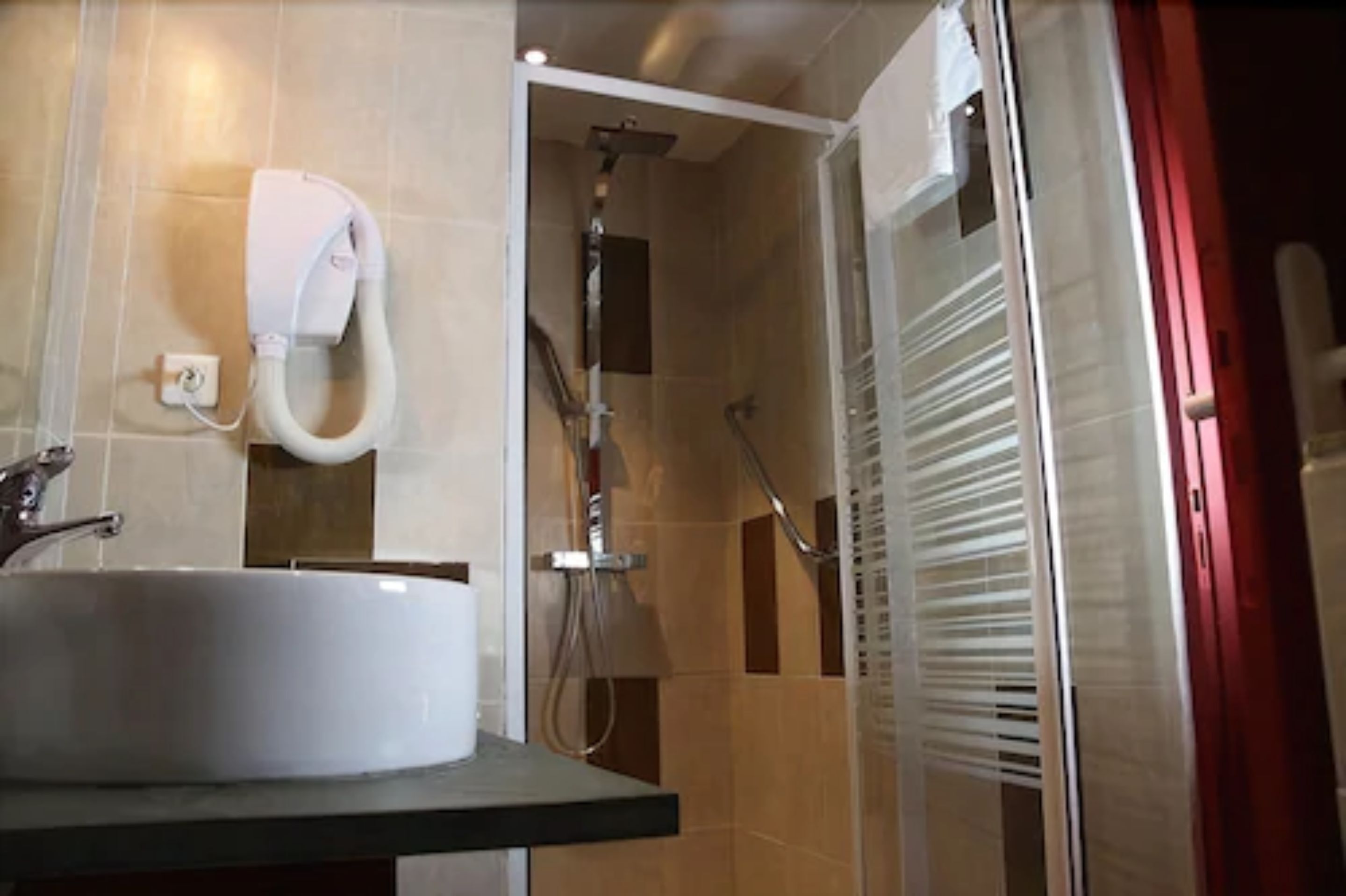 A bathroom with a sink, a handheld showerhead, and a glass shower enclosure.