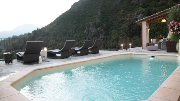 Un área de piscina con sillones de descanso y una pérgola adornada con flores.