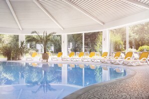 A pool area with lounge chairs and potted plants.