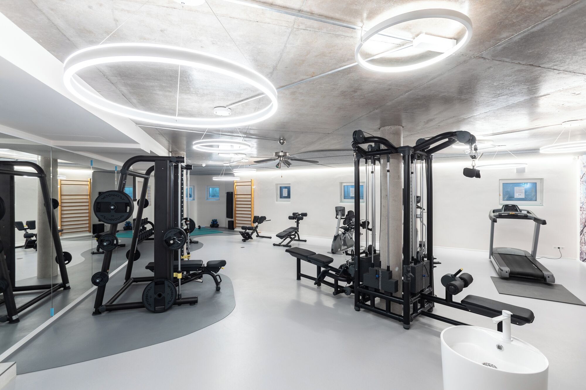 A modern gym with various exercise equipment, a treadmill, and a large mirror.