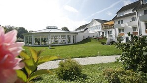 A modern residential area with a large house featuring a glass conservatory, a well-maintained lawn, and a paved driveway. - Hotel Traube Revital (Wurmlingen)