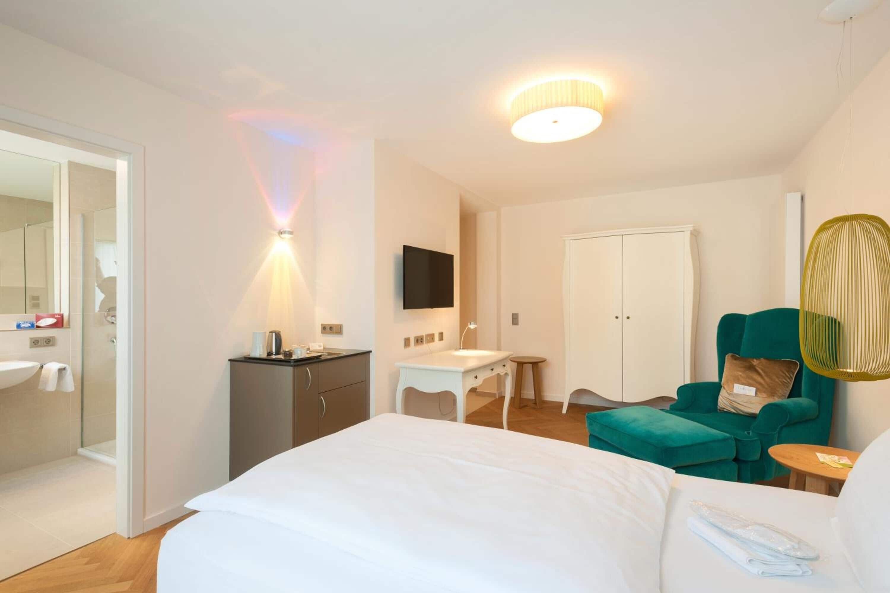 Una habitación de hotel con cama, escritorio, silla, televisor y armario.