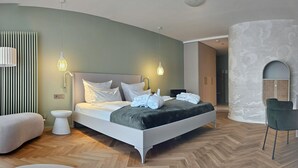 A modern bedroom with a bed, bedside lamps, a radiator, a chair, and a wall with a textured pattern. - Hotel Traube Revital (Wurmlingen)