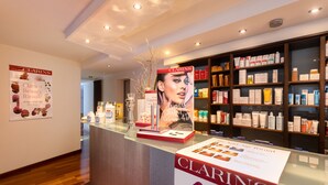 A store interior with a glass counter displaying Clarins products, wooden shelves stocked with various items, and a wooden floor. - Hotel Traube Revital (Wurmlingen)
