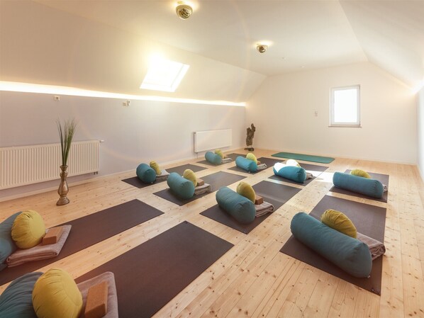 A yoga studio with wooden floors, yoga mats, and colorful cushions.