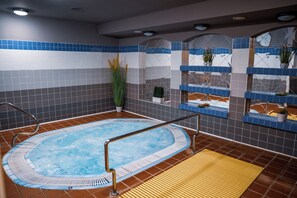 A hot tub area with a tiled wall, a wooden floor mat, and potted plants. - Hotel Zátiší (Spindleruv Mlyn)