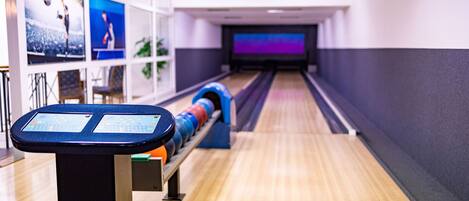 A bowling alley with a wooden floor, a bowling lane, and a bowling ball return system.