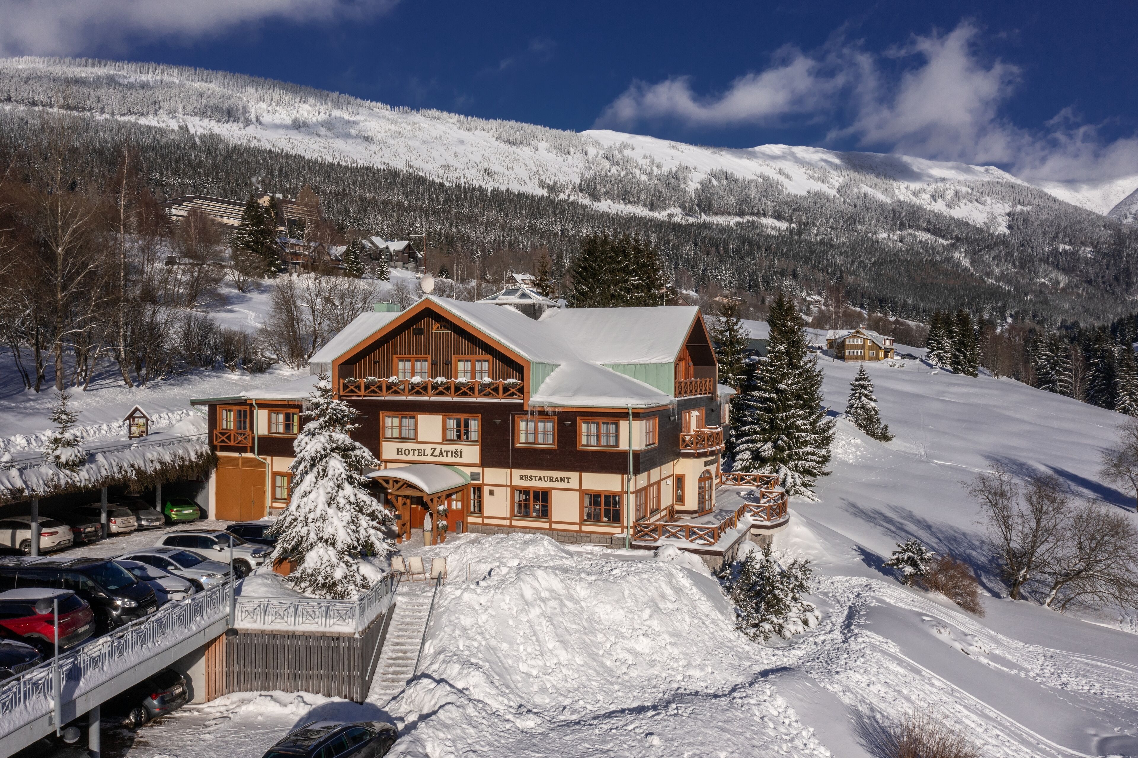 A large wooden building with a restaurant and hotel named "Hotel Zatiş" in a snowy mountainous area.