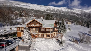 A large wooden building with a restaurant and hotel named "Hotel Zatiş" in a snowy mountainous area.