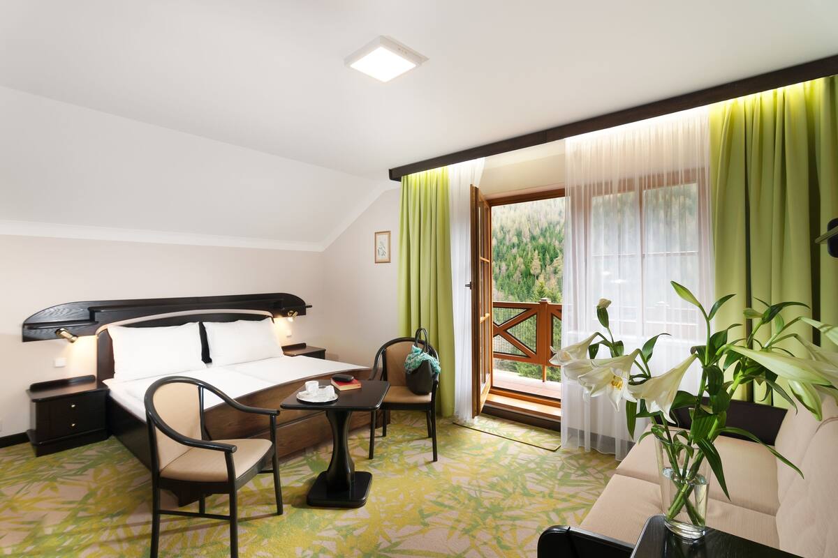 Quarto de hotel com cama, escrivaninha, cadeira, mesa e varanda com vista.