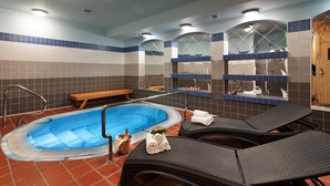 A spa area with a hot tub, lounge chairs, and a wooden bench. - Hotel Zátiší (Spindleruv Mlyn)