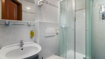 A bathroom with a white sink, a glass shower enclosure, and a toilet.