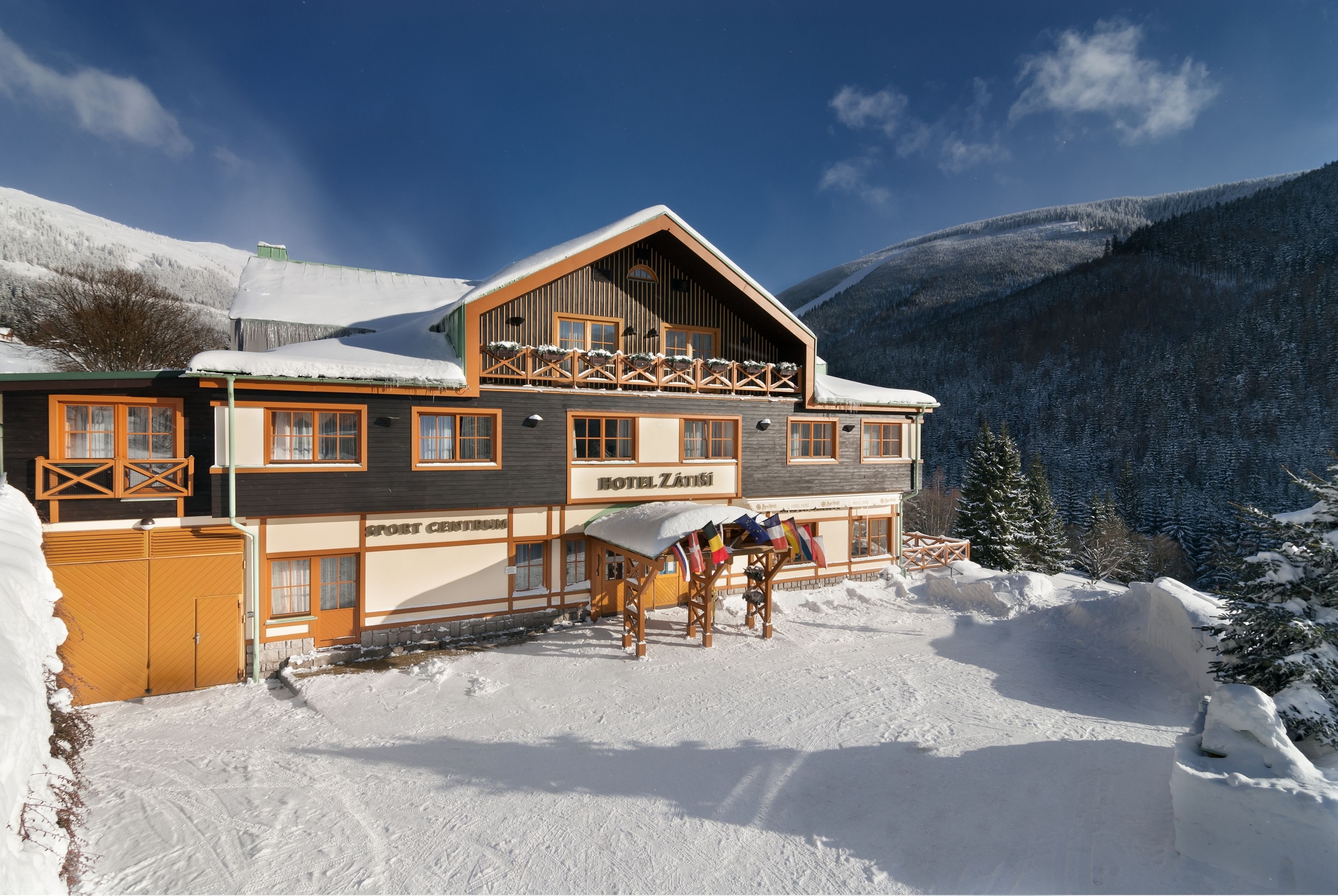 A two-story wooden building with a ski lift and a sign reading "Hotel Zátiší".