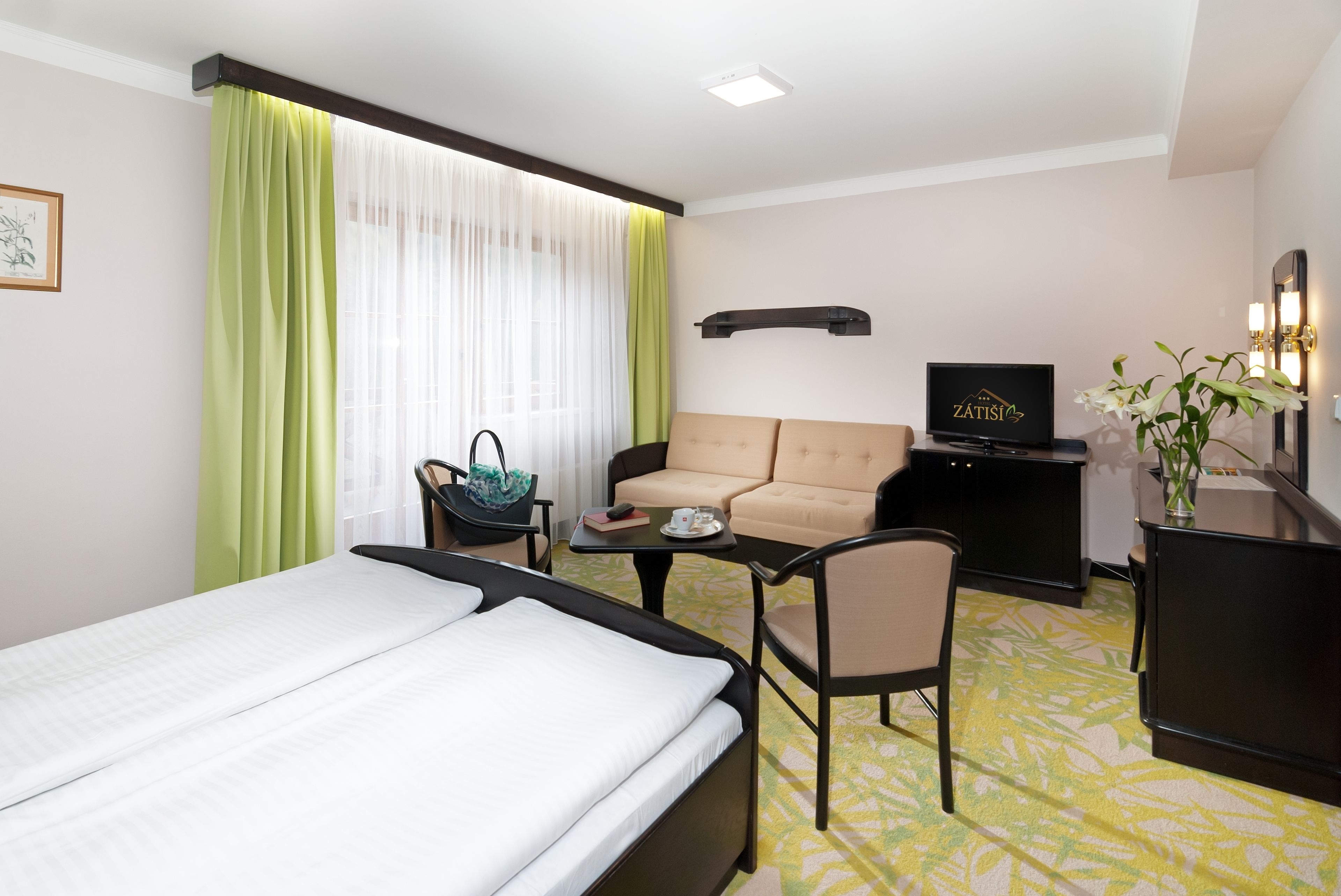 Une chambre d’hôtel comprenant un lit, un canapé, un bureau avec une télévision et une chaise.