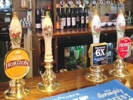 A bar counter with various beer taps, including brands like Horizon and Henrys.