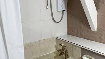 A bathroom with a bathtub, a shower, a toilet, and a towel dispenser.