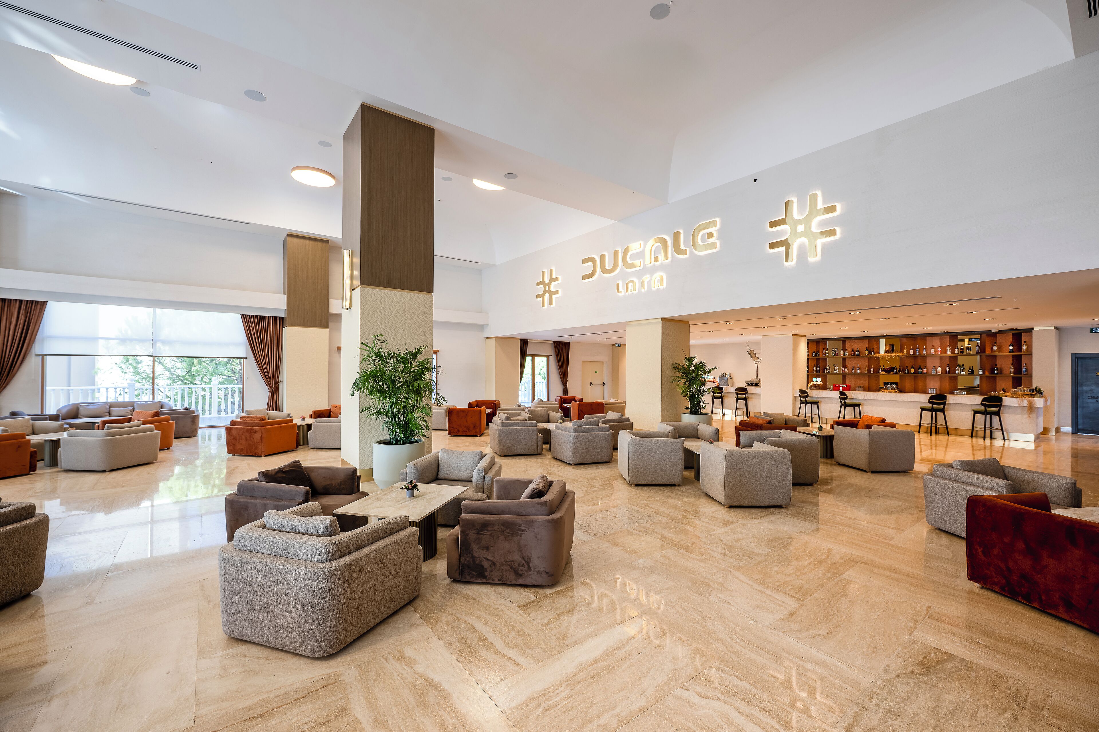 A spacious lobby with multiple seating areas, a reception desk, and a bar area.