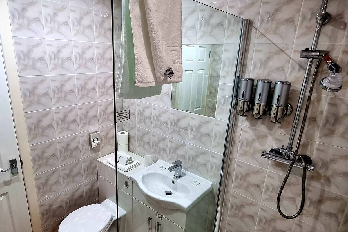 A bathroom with a glass-enclosed shower, a sink, and a toilet.
