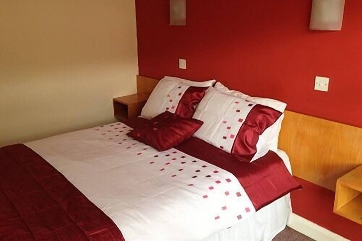 A bed with a red and white bedspread, two pillows, and a wooden headboard.