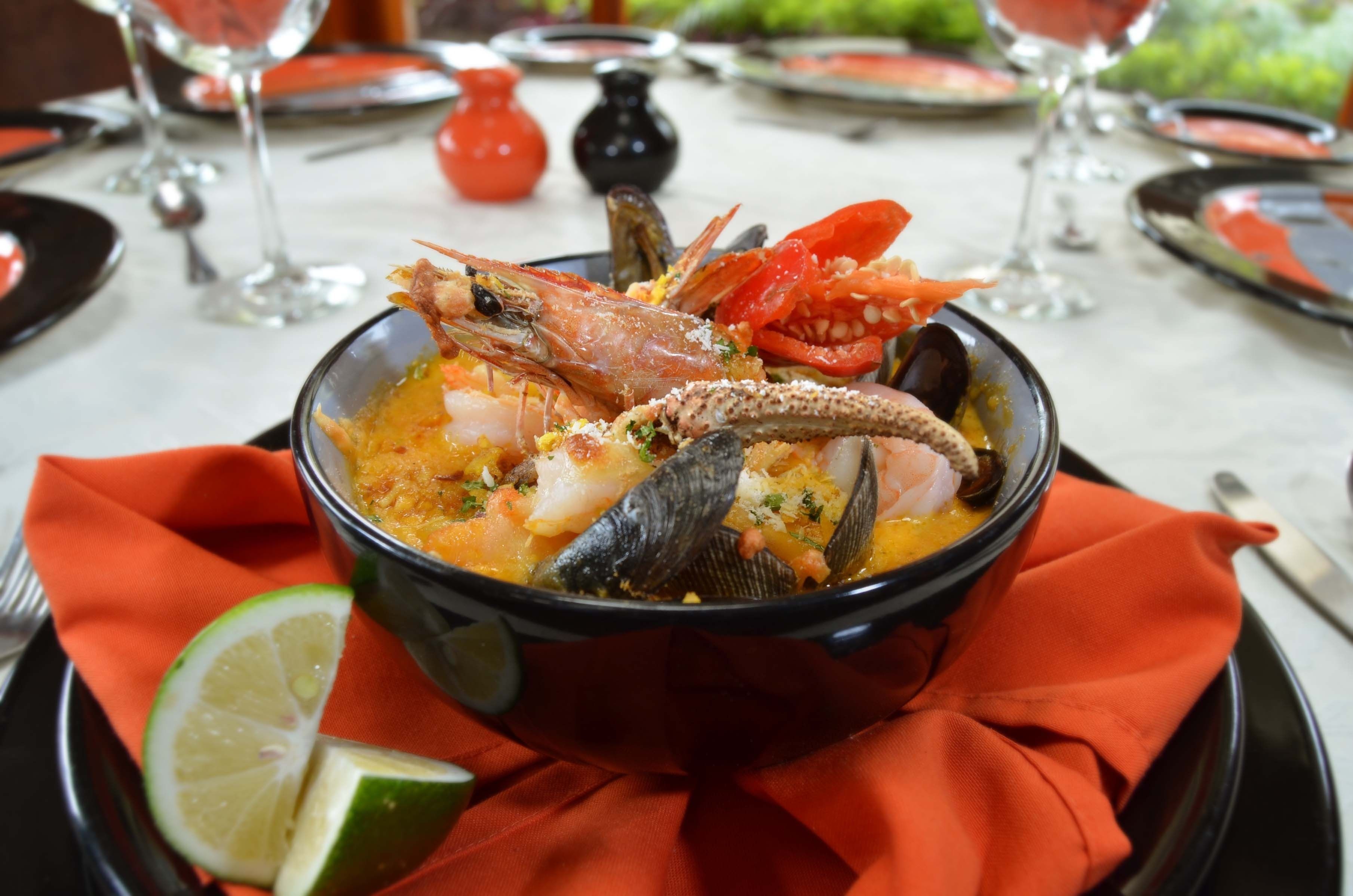 A seafood dish in a bowl, accompanied by a lime wedge and a red napkin.