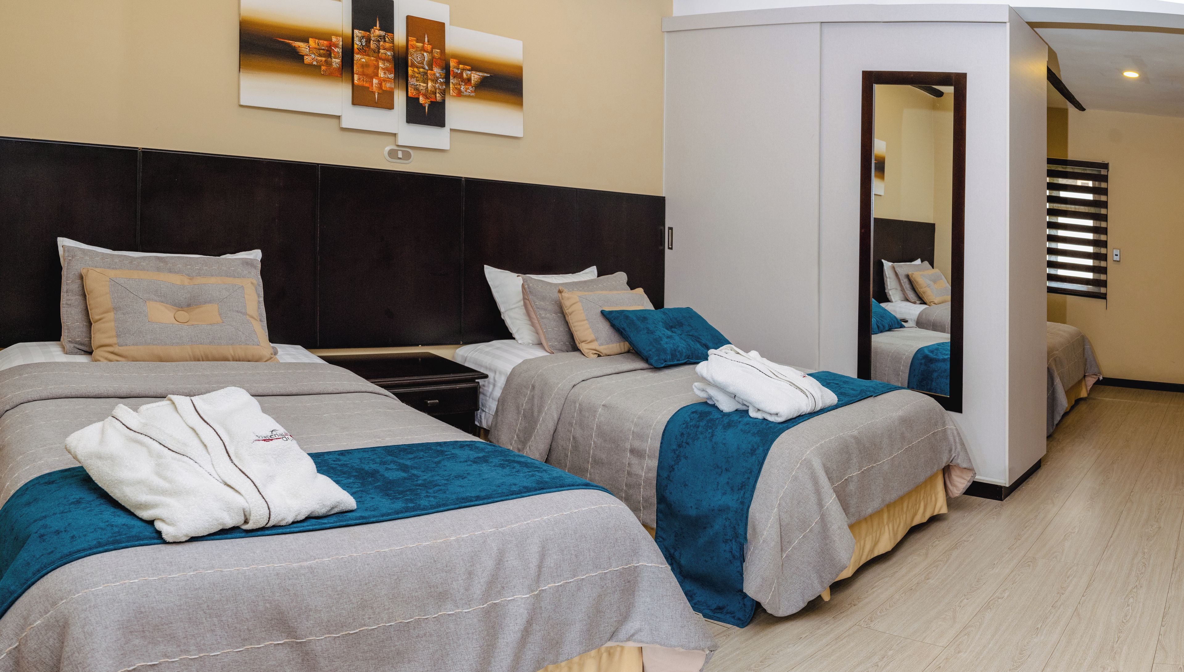 A hotel room with two beds, each with a headboard, bedside tables, and towels.