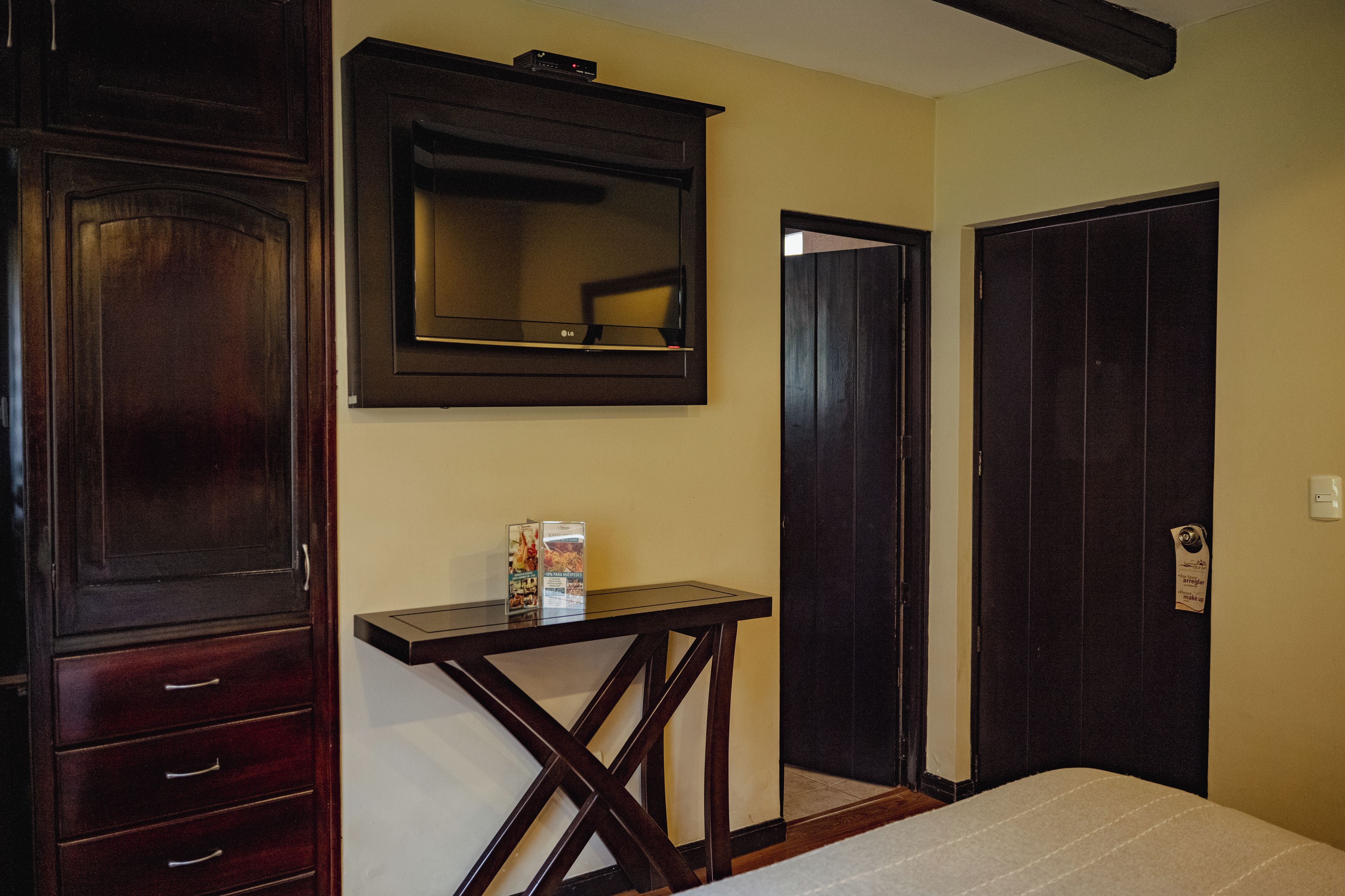A bedroom with a bed, a dresser, a mirror, and a small table with a box on it.