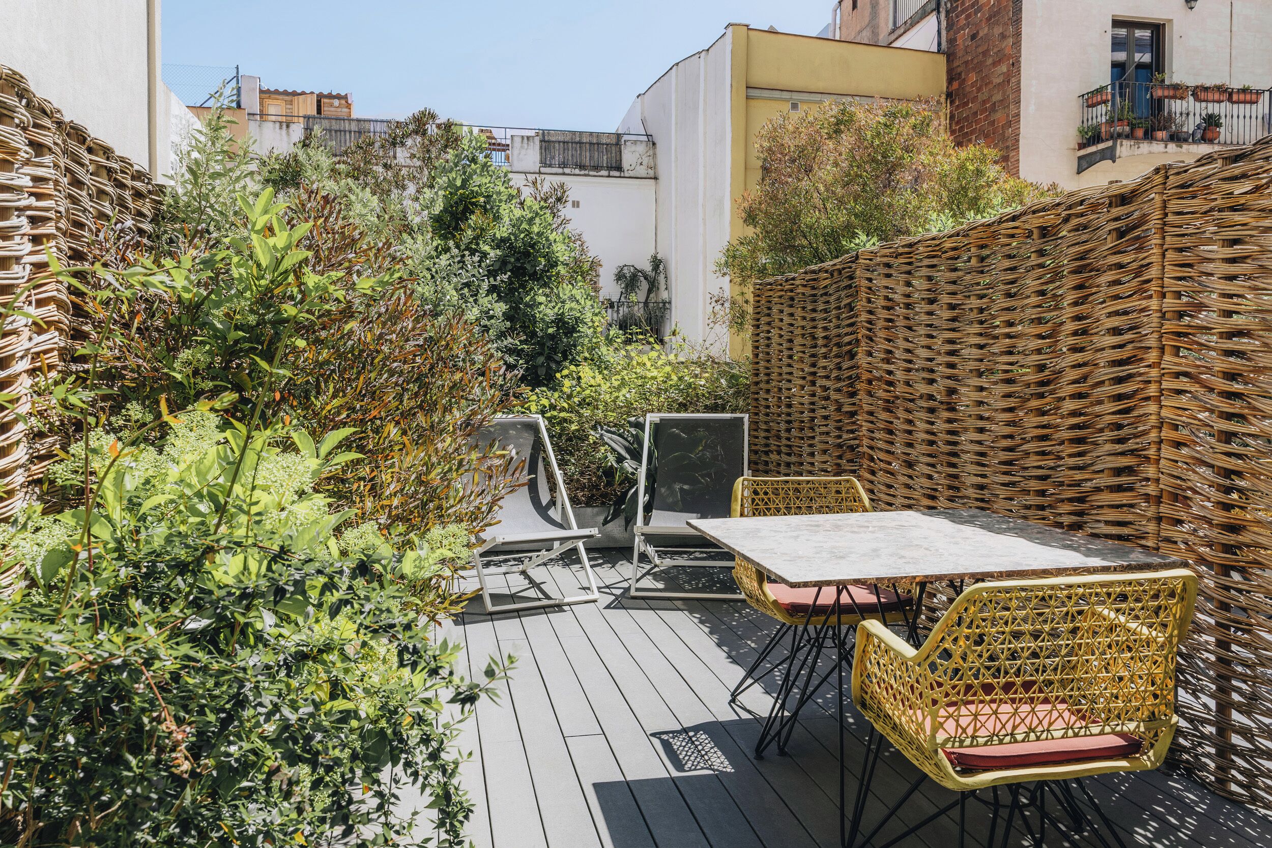 Un patio al aire libre con muebles de mimbre, una mesa y sillas.