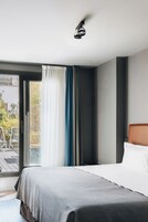 Quarto de hotel com cama, janela com cortinas, luminária no teto e vista para o exterior.