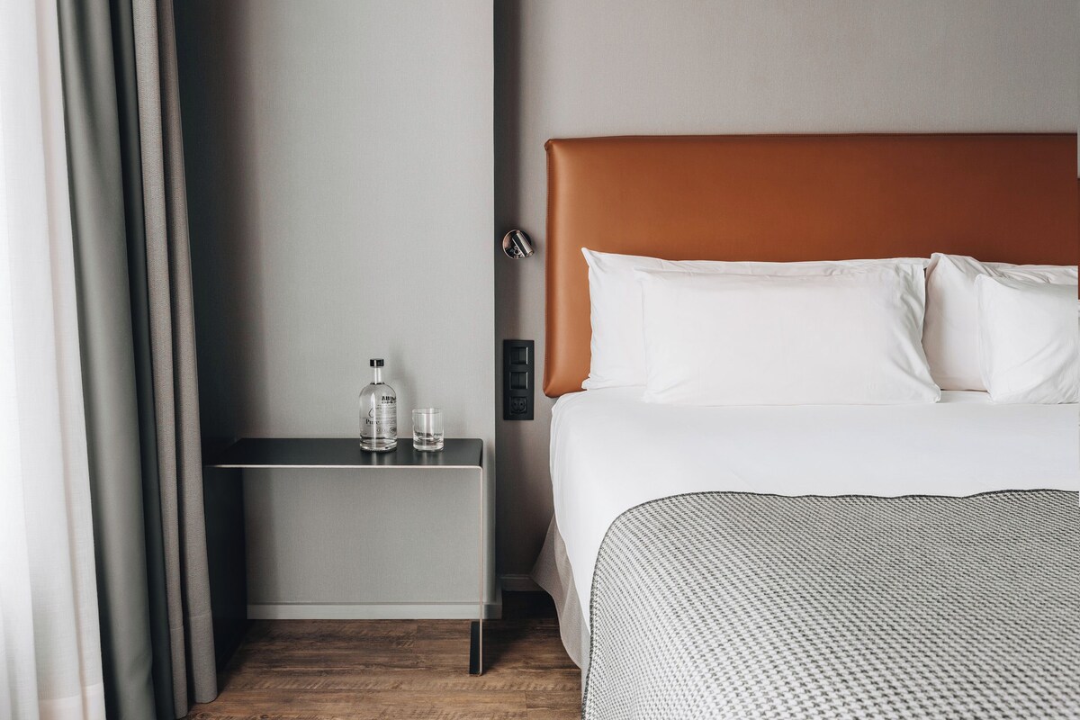 Ein Hotelzimmer mit Bett, Nachttisch, Flasche und Glas.