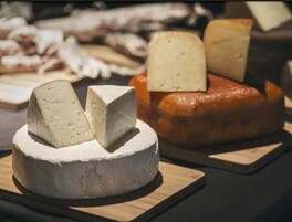 A cheese board with various types of cheese and a loaf of bread.
