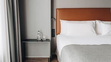 Una habitación de hotel con cama, mesita de noche, una botella y un vaso.