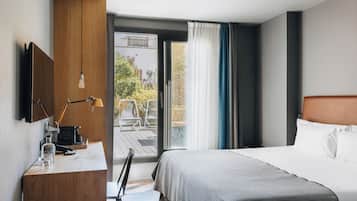 Habitación de hotel con cama, escritorio con lámpara, televisión y vistas al exterior.