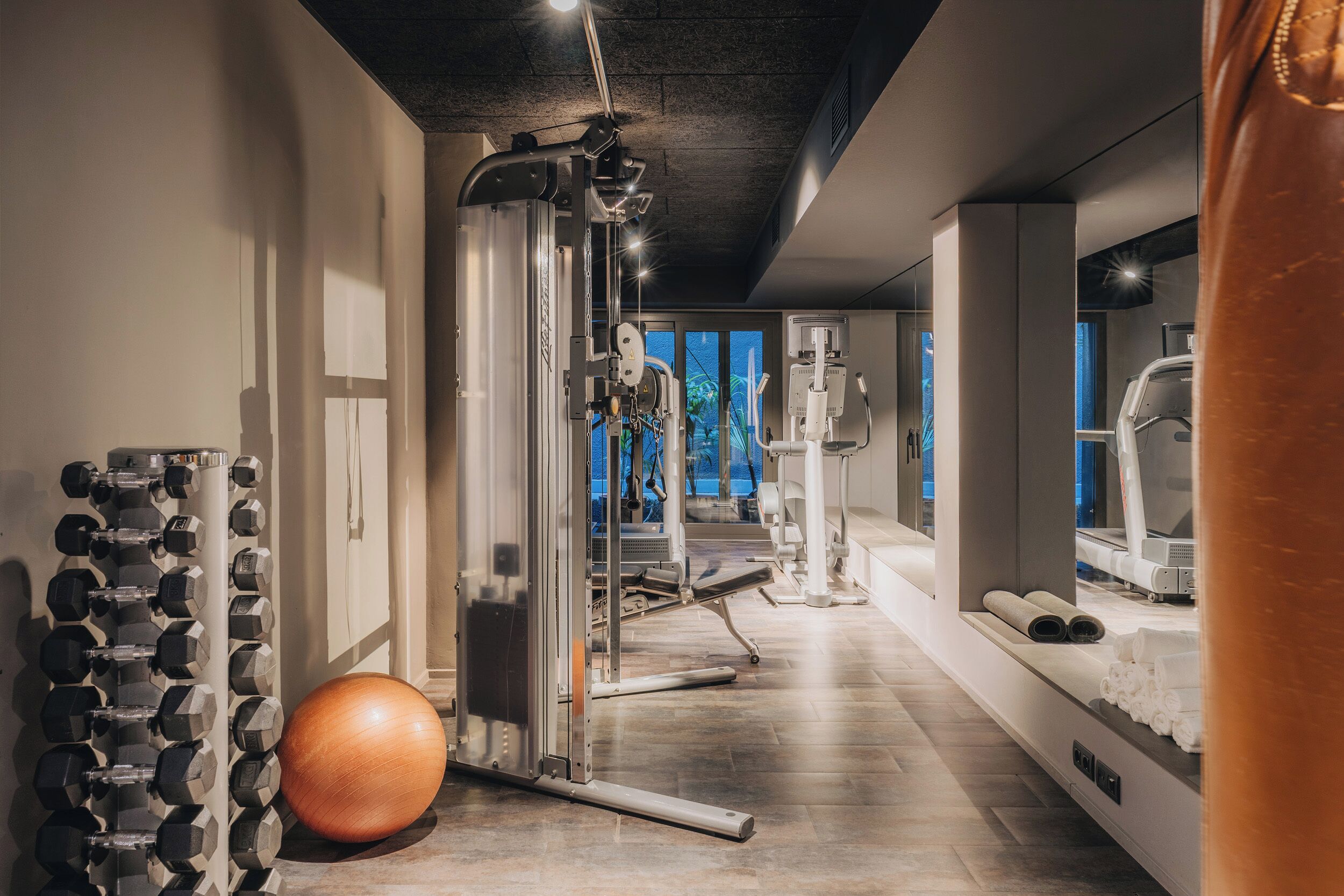 Un gimnasio con equipo de ejercicio, una pared de mancuernas y una pelota de ejercicios grande.
