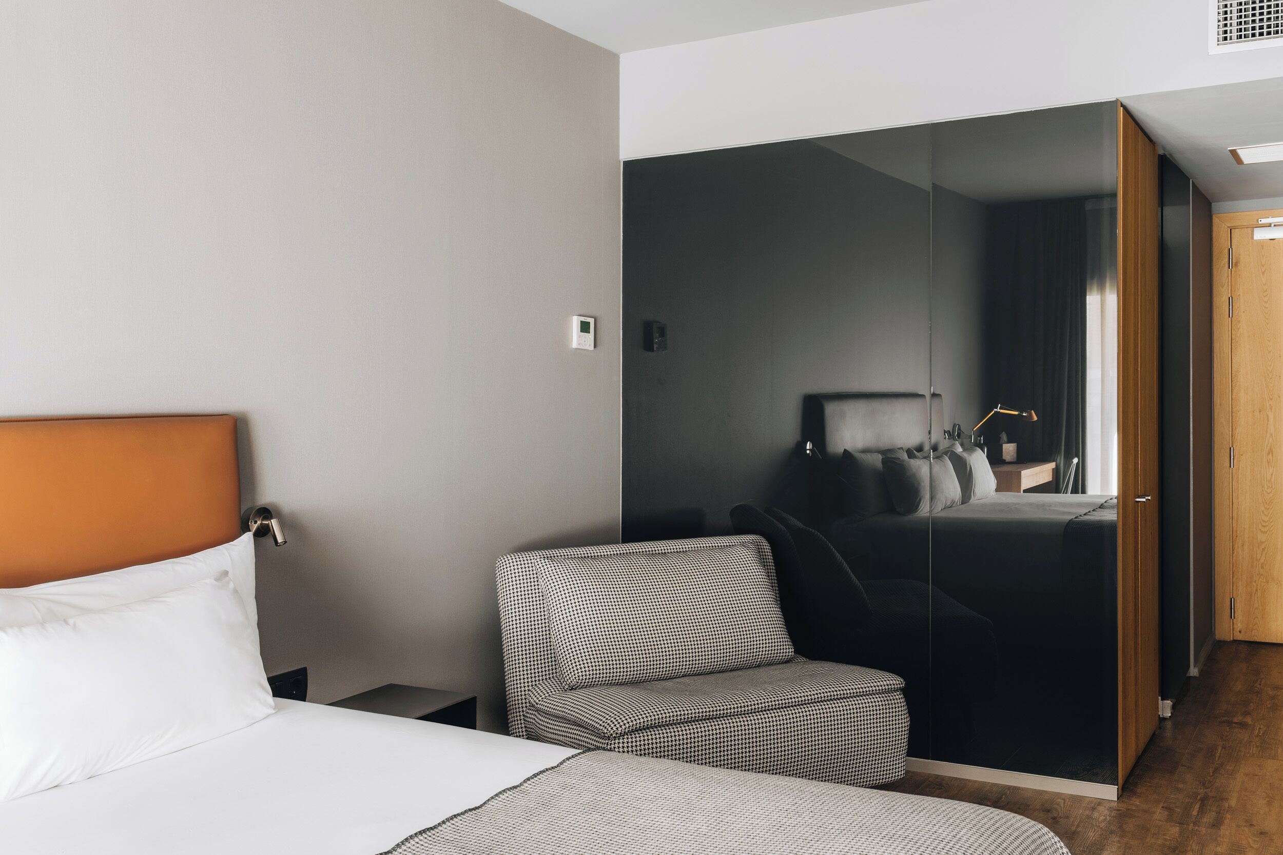Quarto de hotel com cama, sofá, guarda-roupa e espelho.