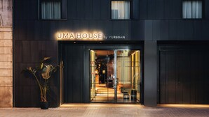 Un bâtiment moderne, avec une enseigne indiquant « UMA HOUSE by YURBBAN » à l’entrée.